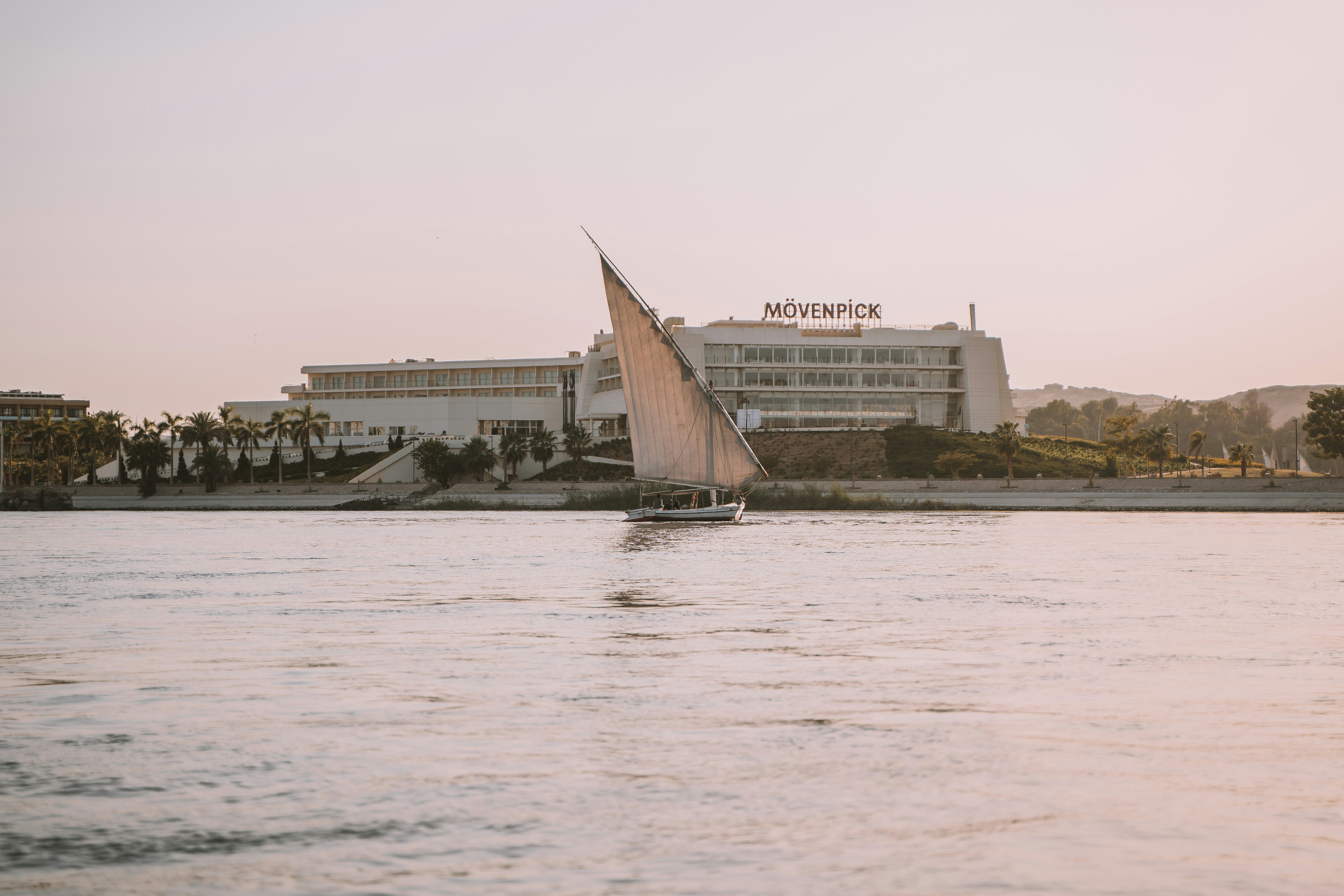 A sailboat on a body of water in front of a hotel