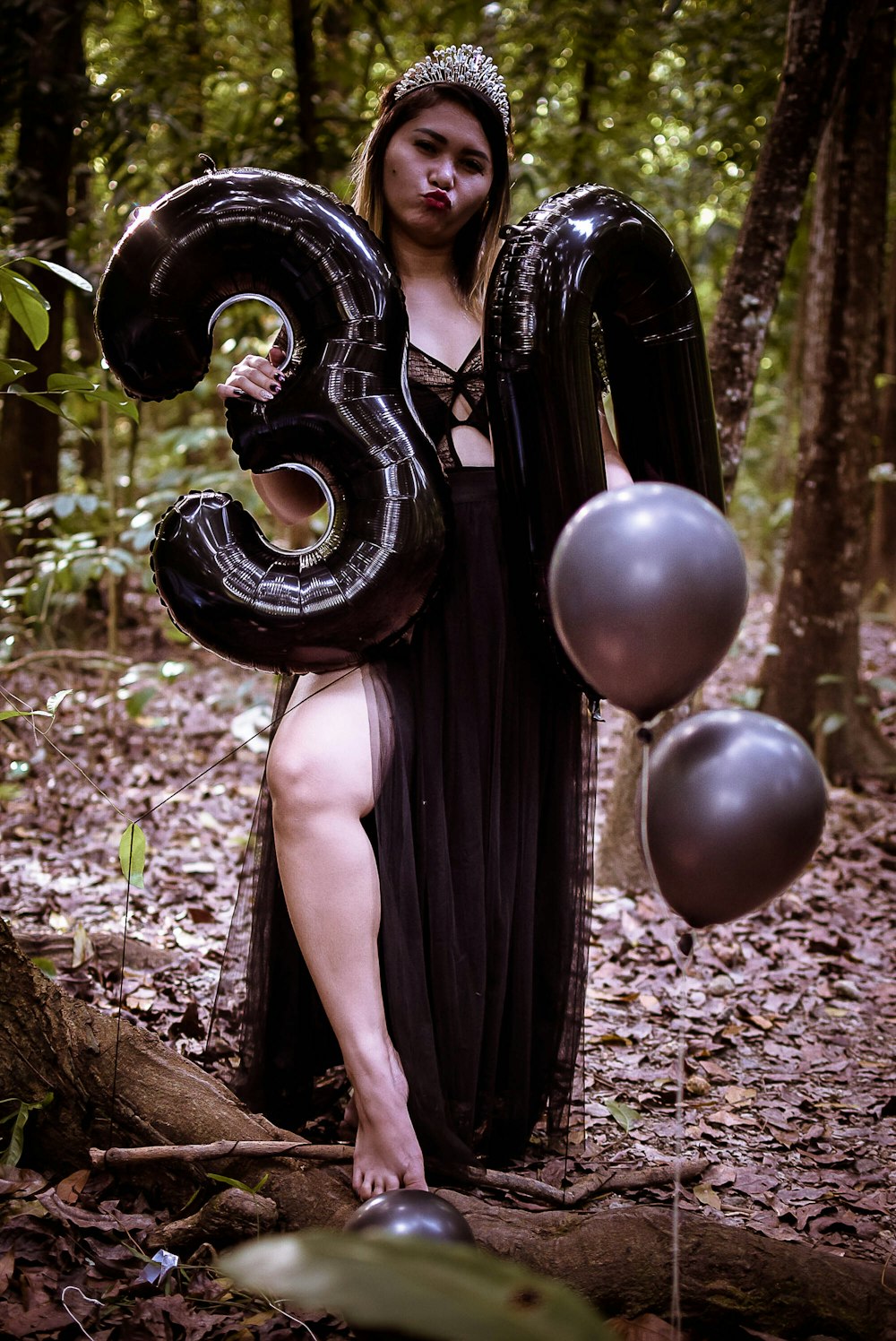 a woman in a black dress holding a number 3 balloon