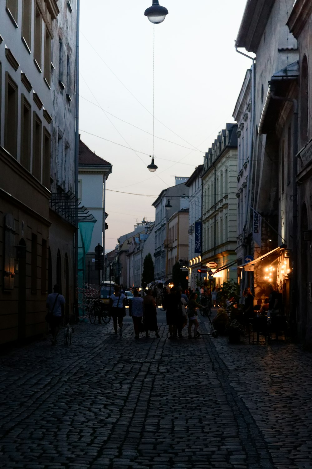 a cobblestone street with people walking down it