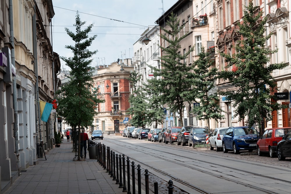 a city street lined with parked cars next to tall buildings