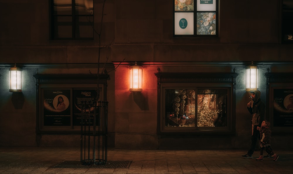 a couple of people walking down a street at night