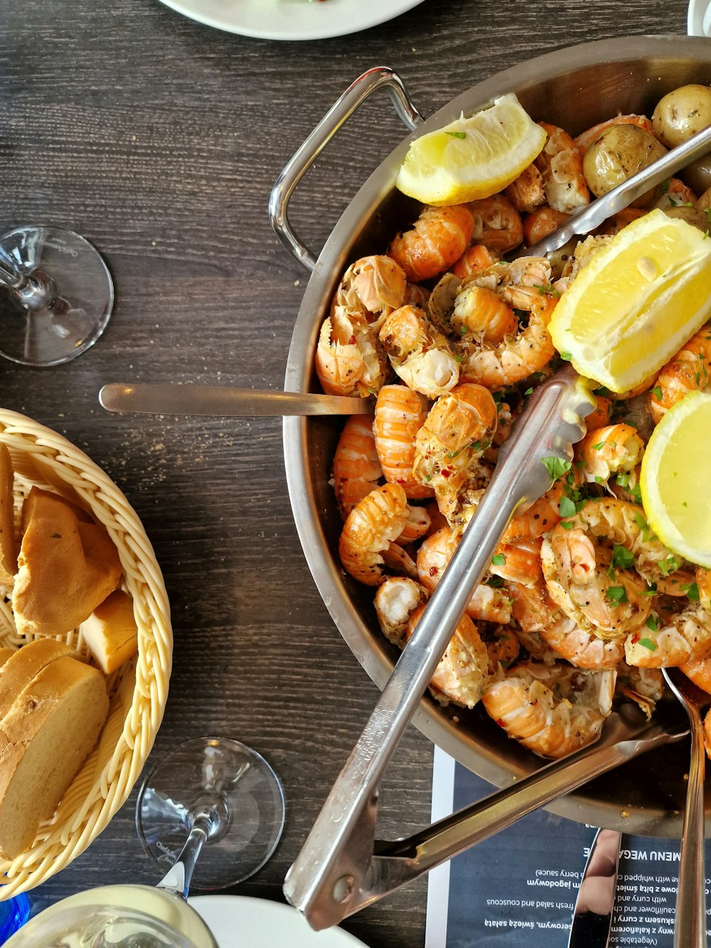 a bowl of food with shrimp and lemon wedges