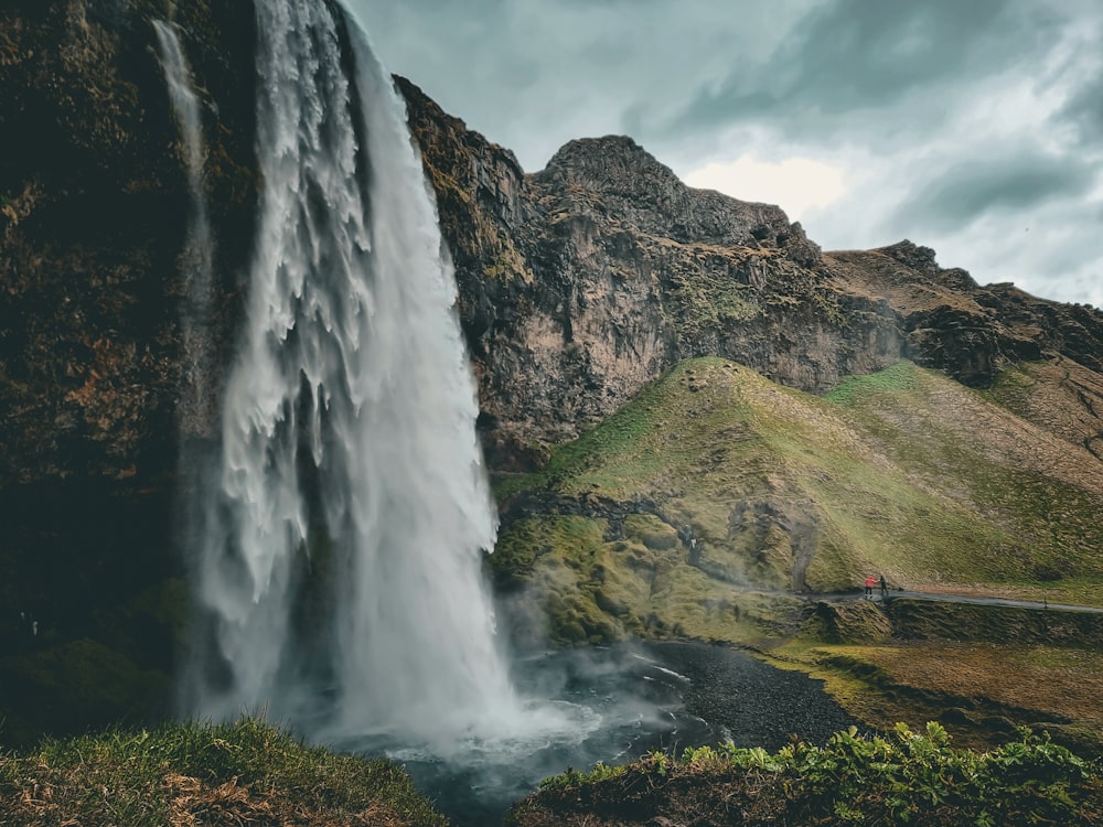 a very tall waterfall with a man standing next to it