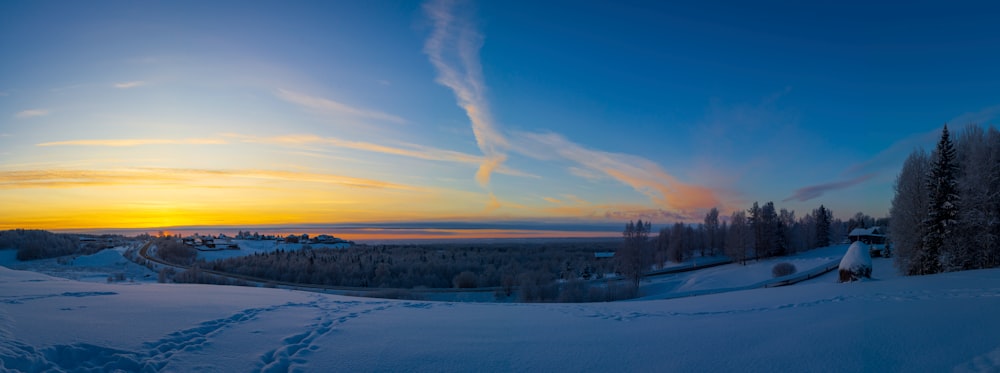 the sun is setting over a snowy landscape