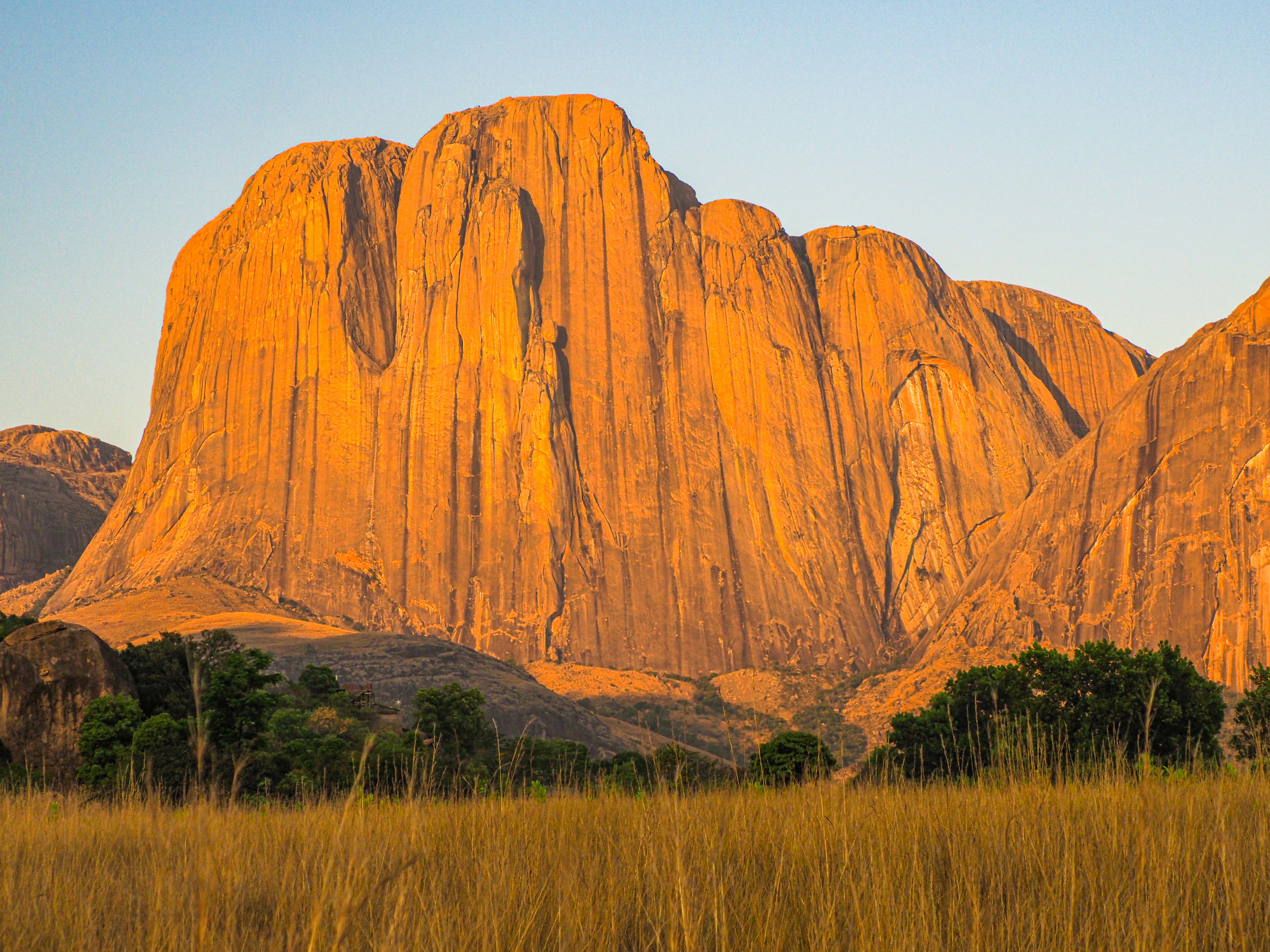 uma grande montanha com grama alta à sua frente