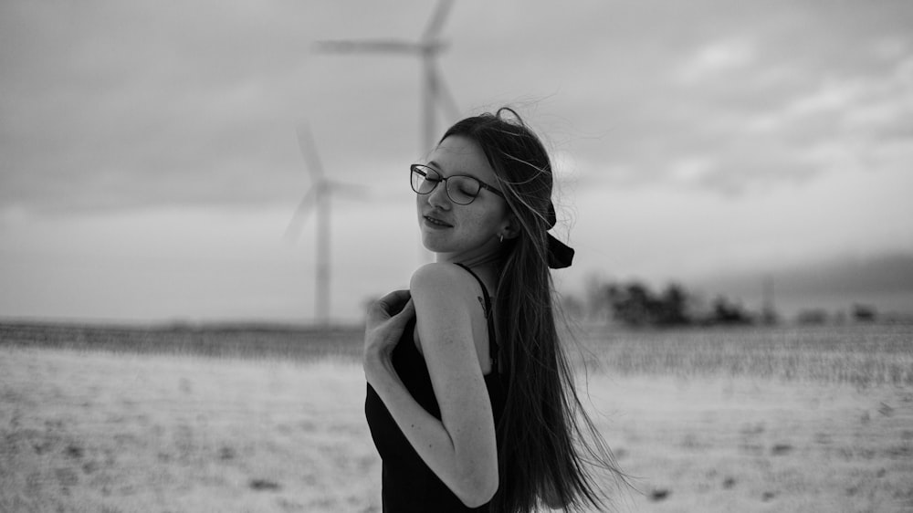 a woman standing in a field with a wind turbine in the background
