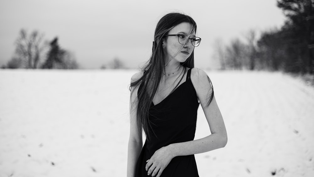 a woman in a black dress standing in the snow