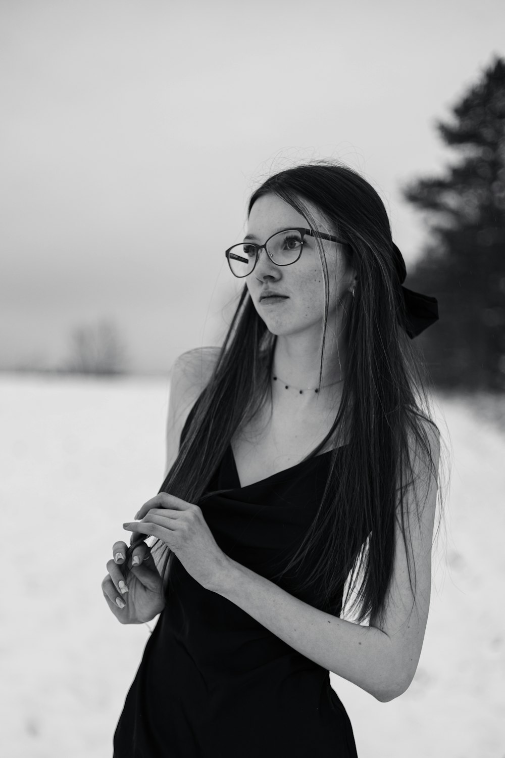 a woman with long hair and glasses standing in the snow