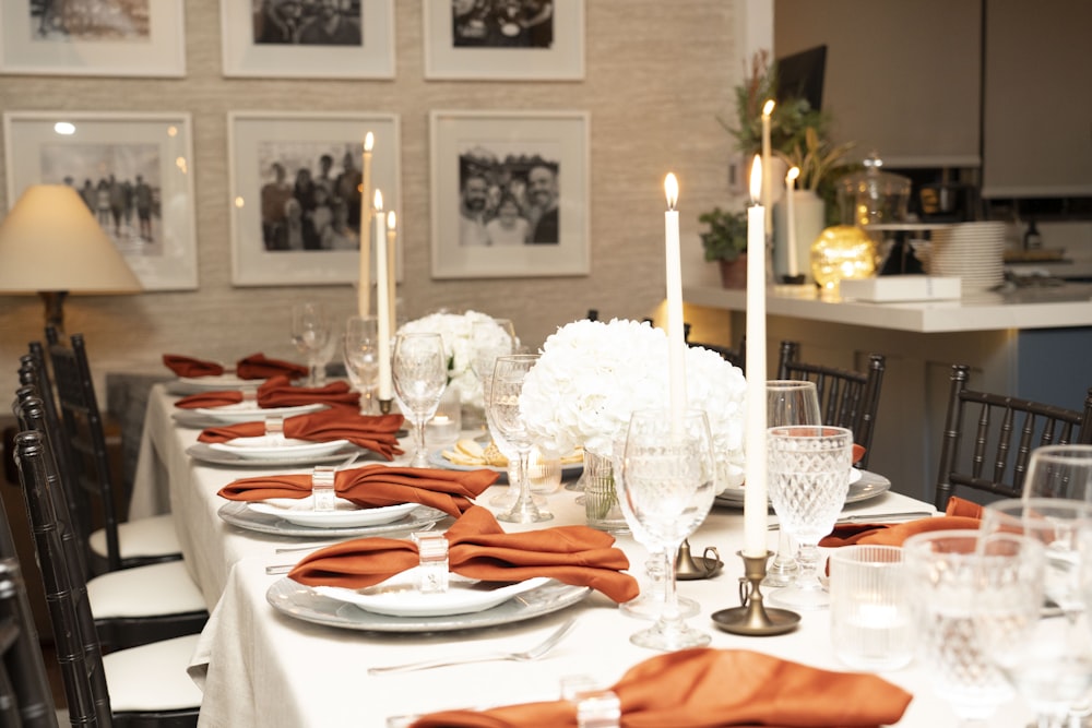 a table set for a formal dinner with orange napkins