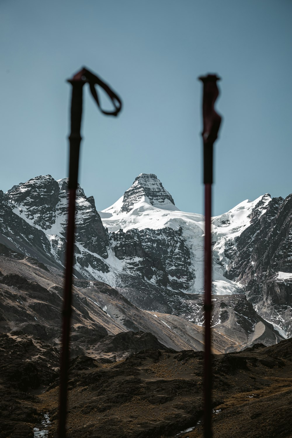 a view of a snowy mountain range through a pair of ski poles