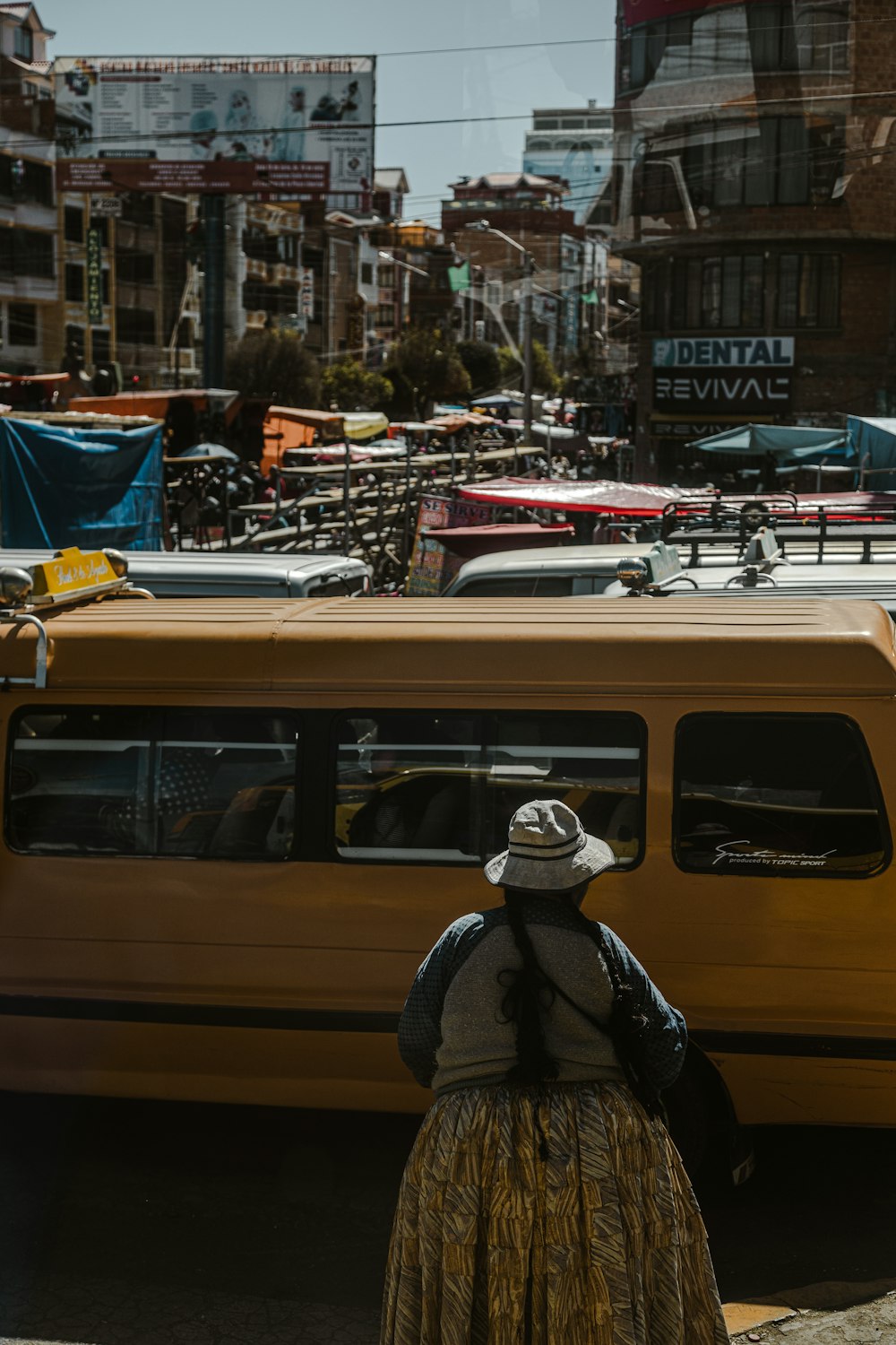 a woman standing in front of a yellow bus