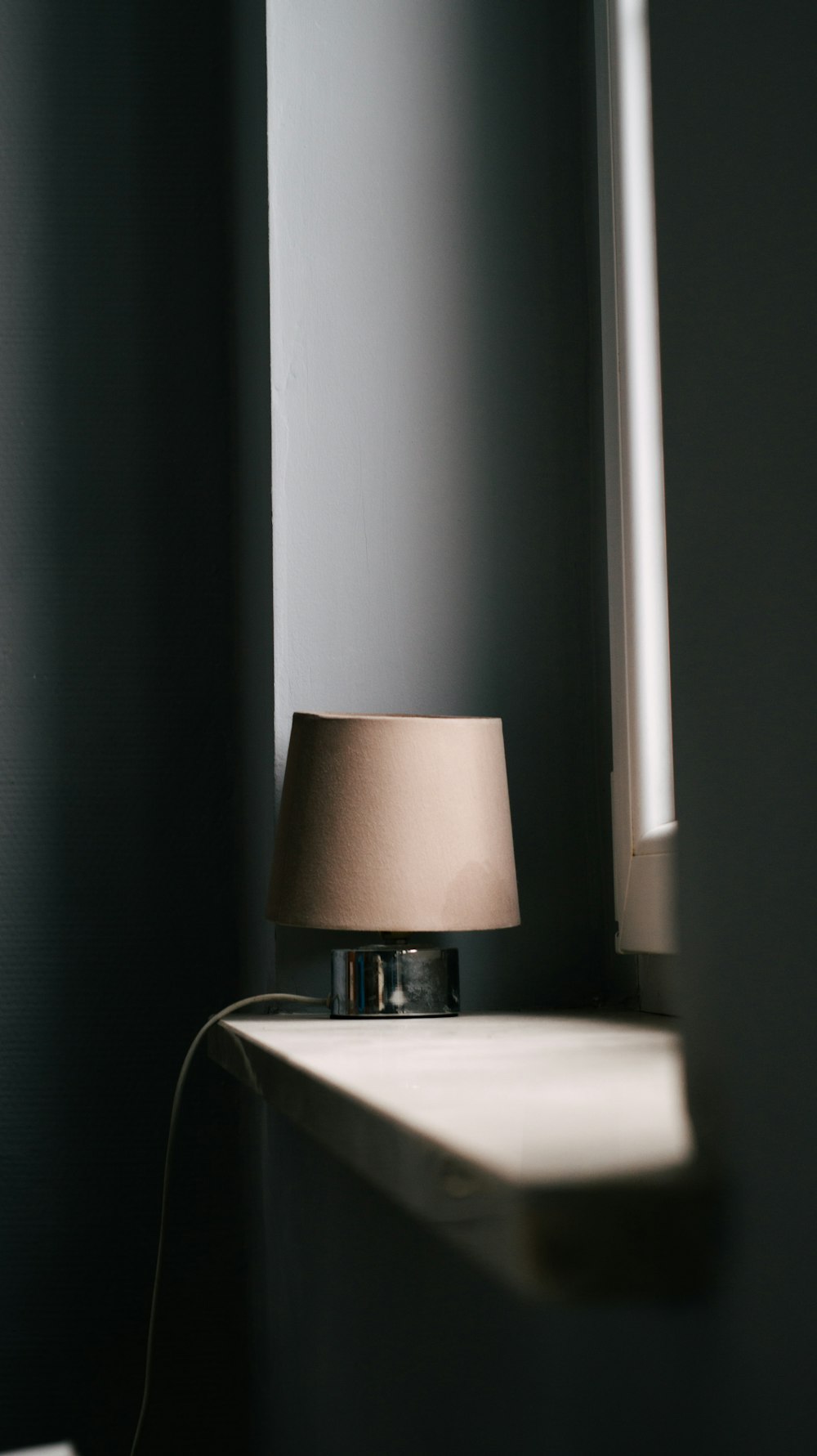 a lamp sitting on top of a shelf next to a window