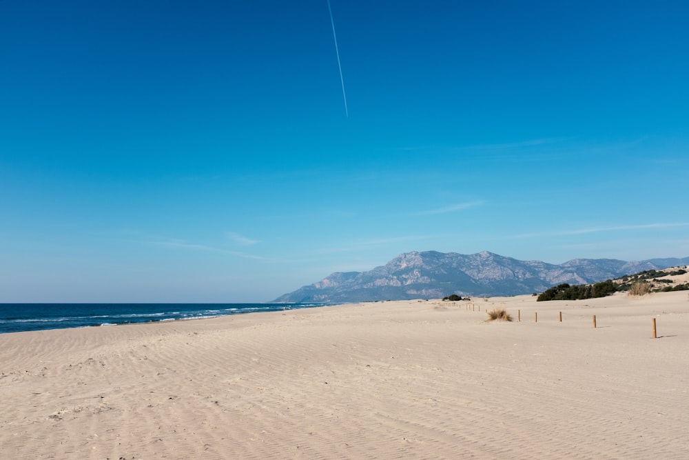 a sandy beach with mountains in the background