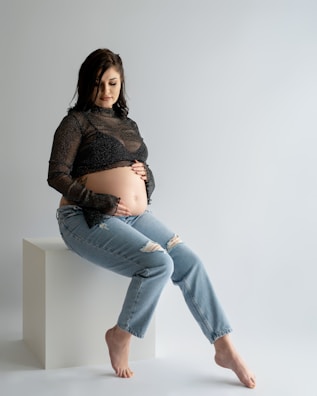 a pregnant woman sitting on a stool