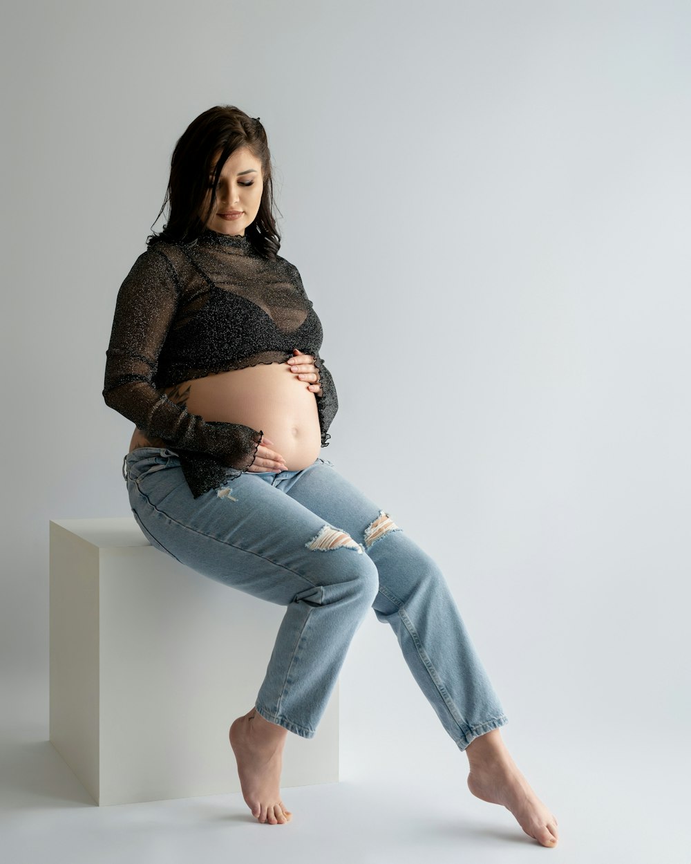 a pregnant woman sitting on a stool