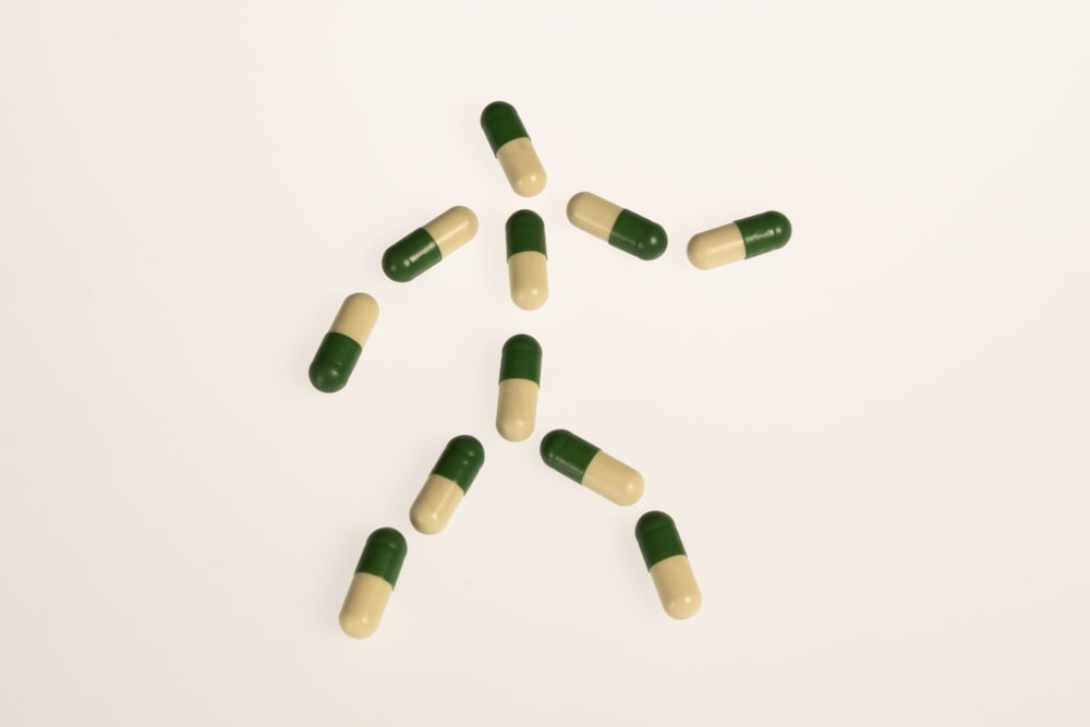 a group of green and white pills on a white surface