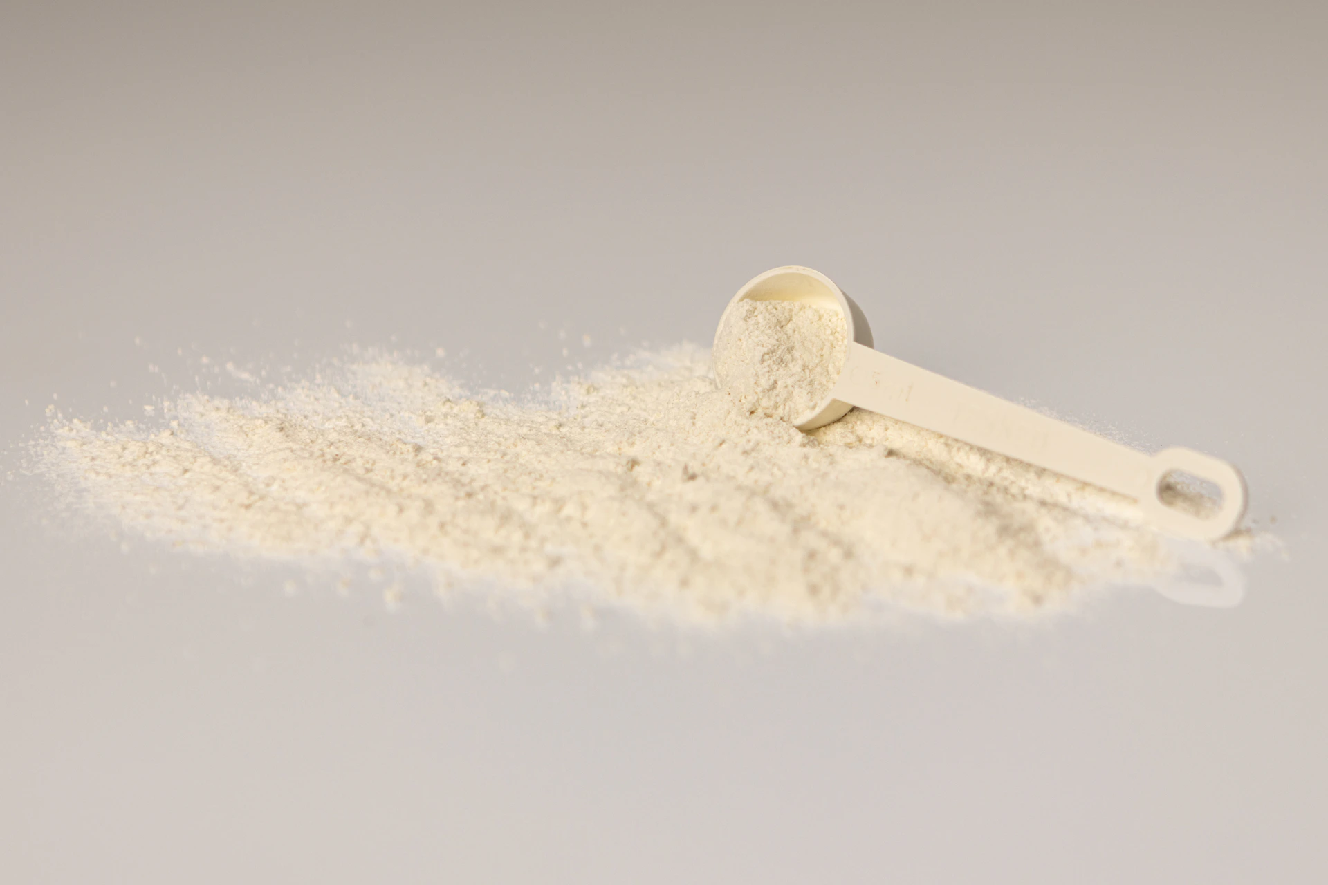 a pile of white powder next to a scoop of powder