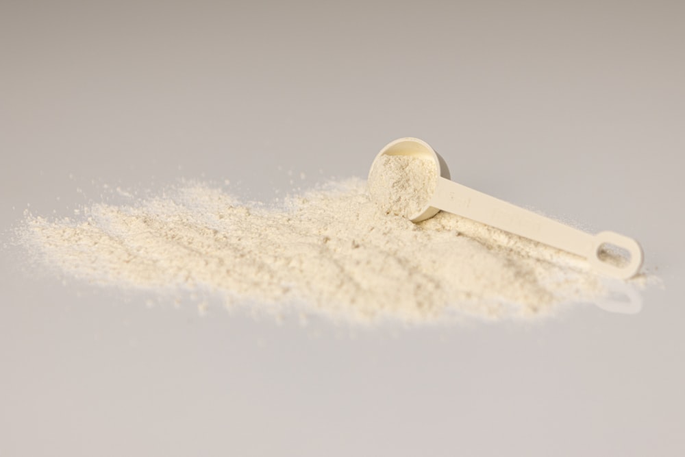 a pile of white powder next to a scoop of powder