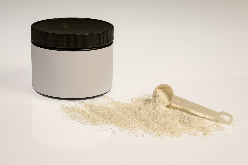 a jar of powder next to a scoop of powder