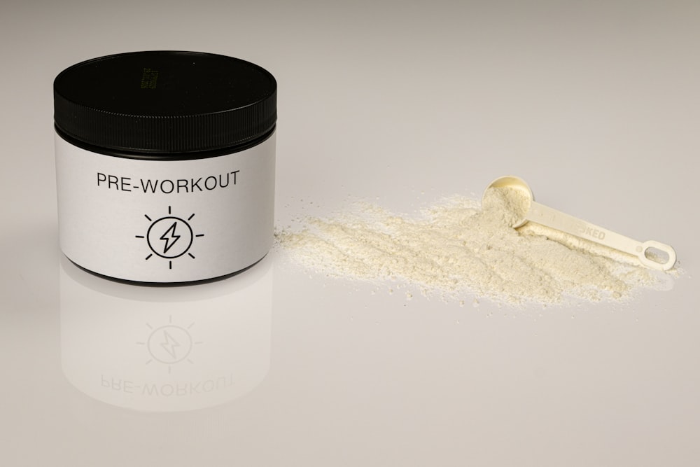 a jar of pre - workout powder next to a scoop of powder