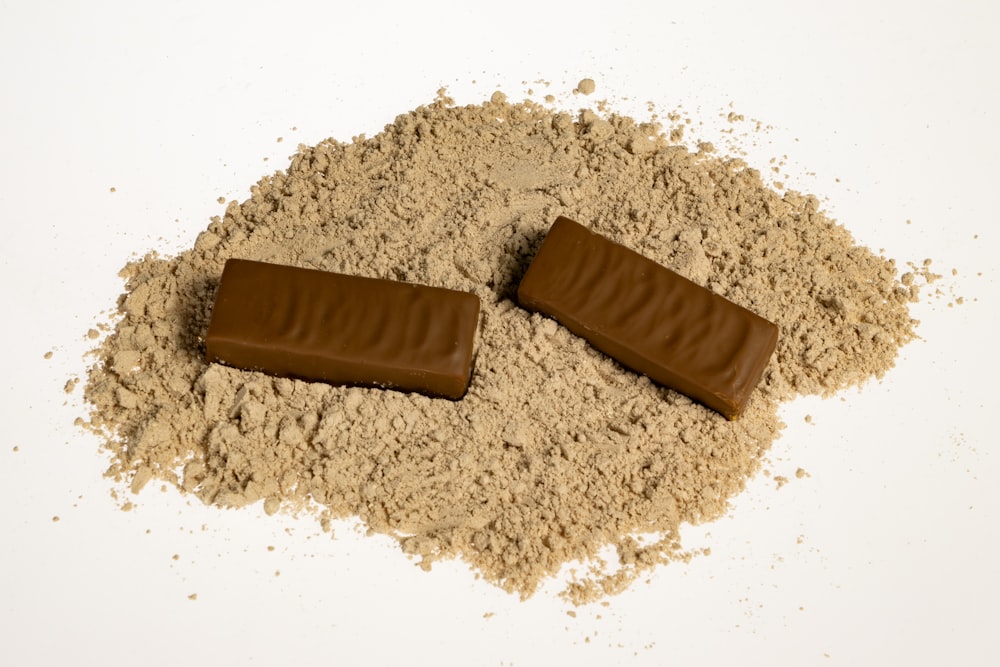 two pieces of chocolate sitting on top of a pile of sand