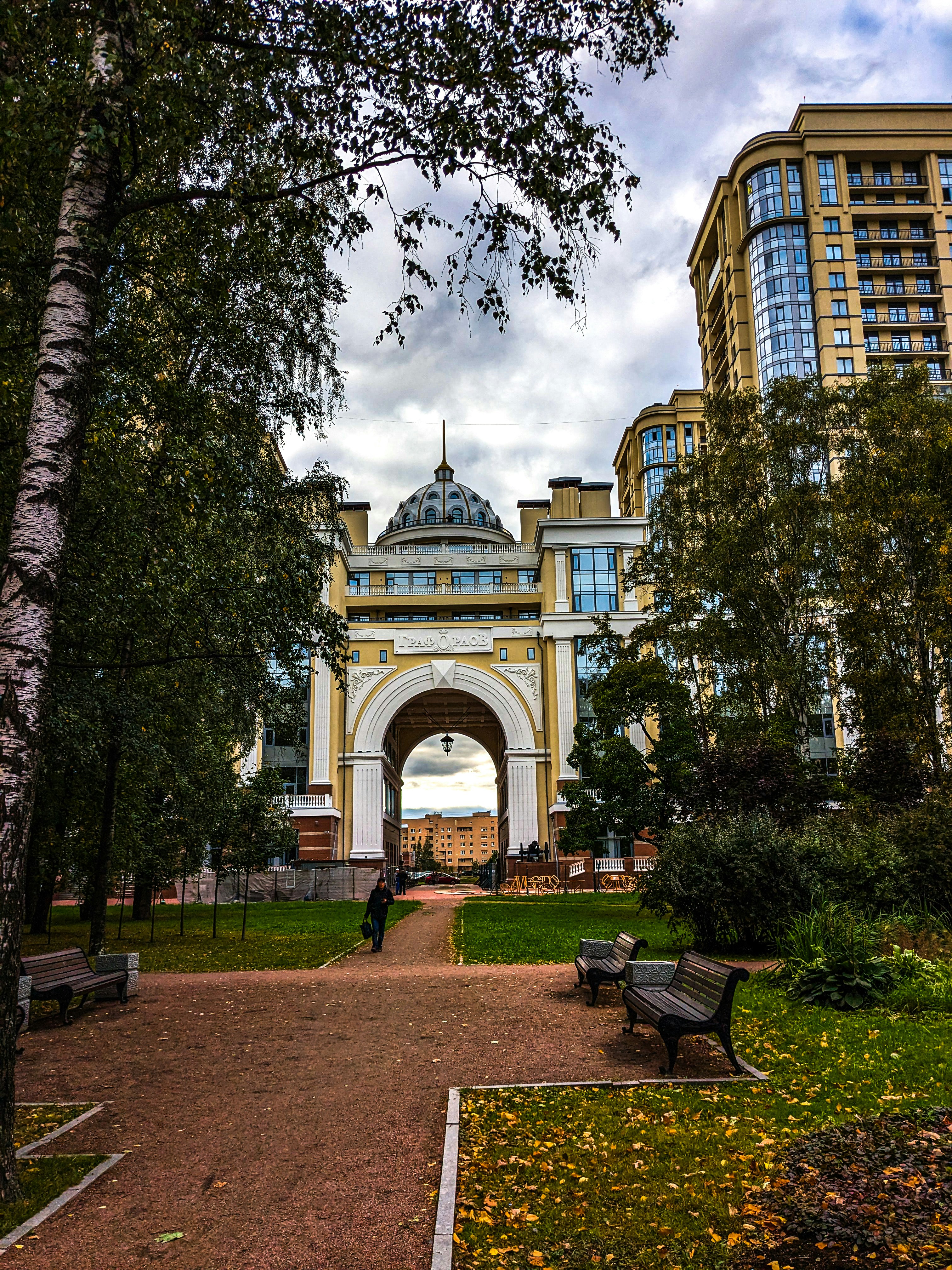 A park with benches and trees in front of a building photo – Free ...