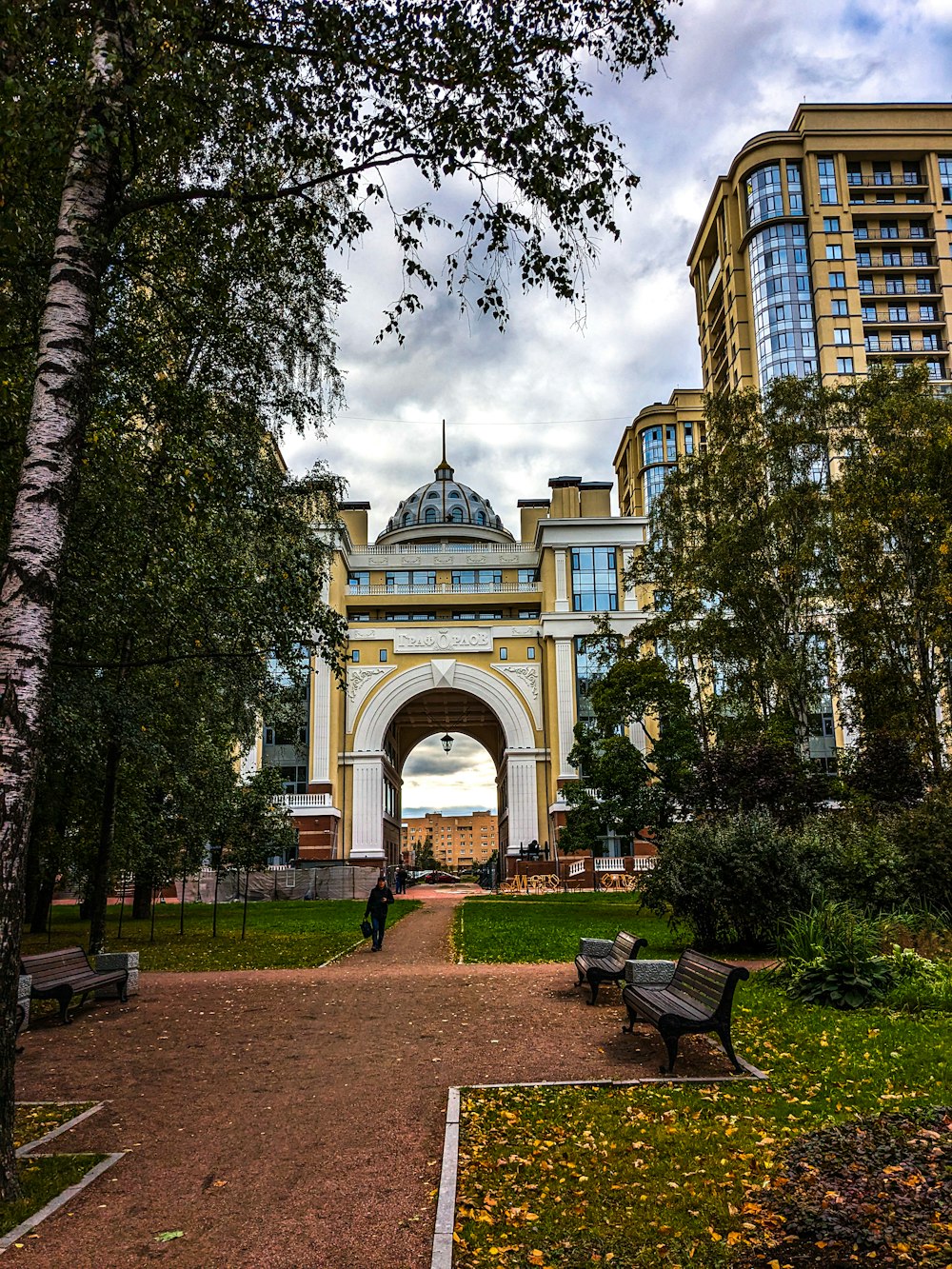 a park with benches and trees in front of a building