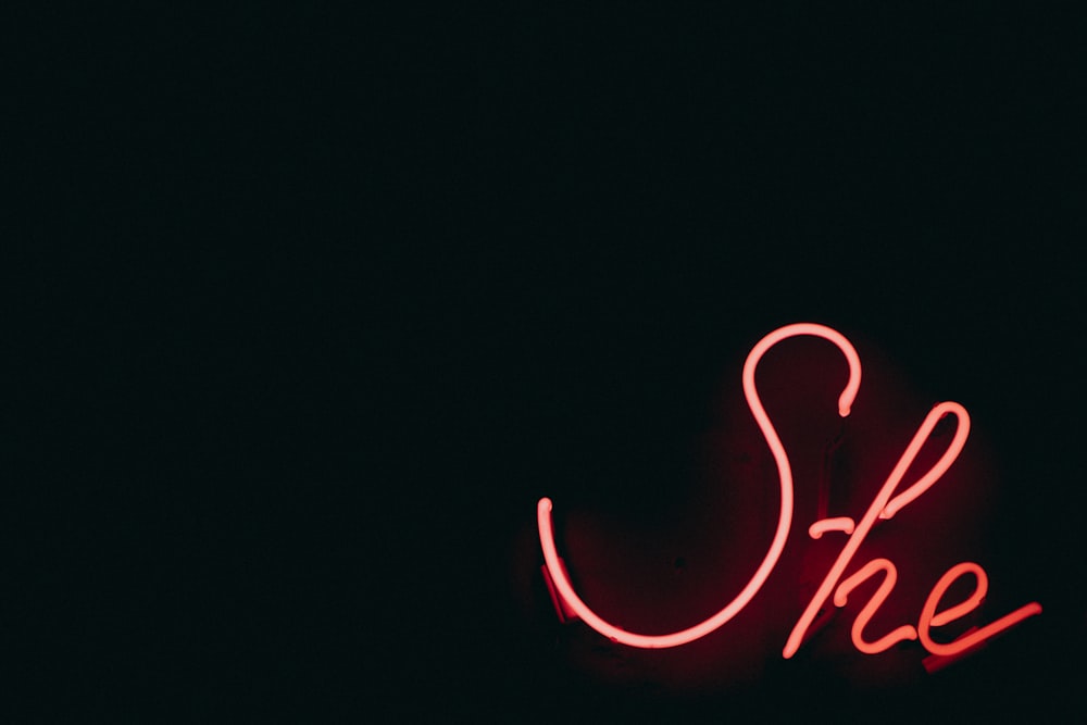 a red neon sign that reads she