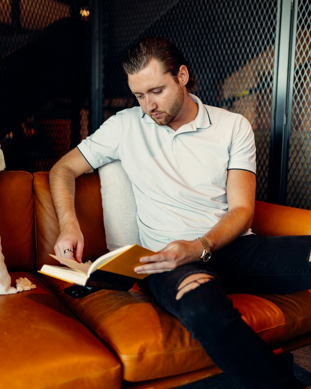 a man sitting on a couch reading a book