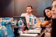 a group of people sitting at a table with laptops