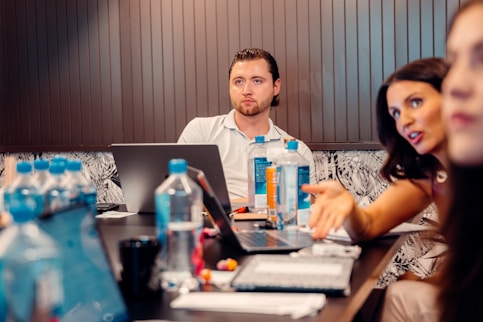 a group of people sitting at a table with laptops