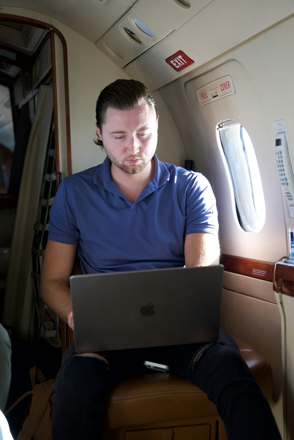 un uomo seduto su un aereo che usa un computer portatile