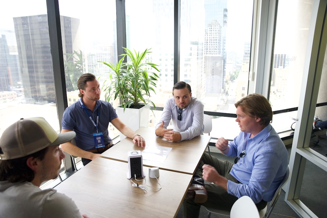 a group of men sitting around a table talking, Working in office