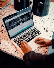 a woman sitting at a table using a laptop computer