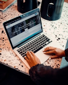 a woman sitting at a table using a laptop computer