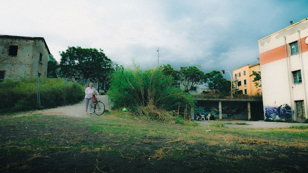 未舗装の道路で自転車の横に立つ男性