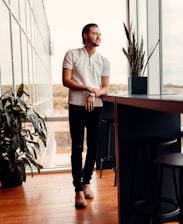 a man standing in front of a window next to a plant