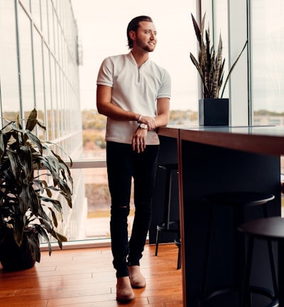 a man standing in front of a window next to a plant