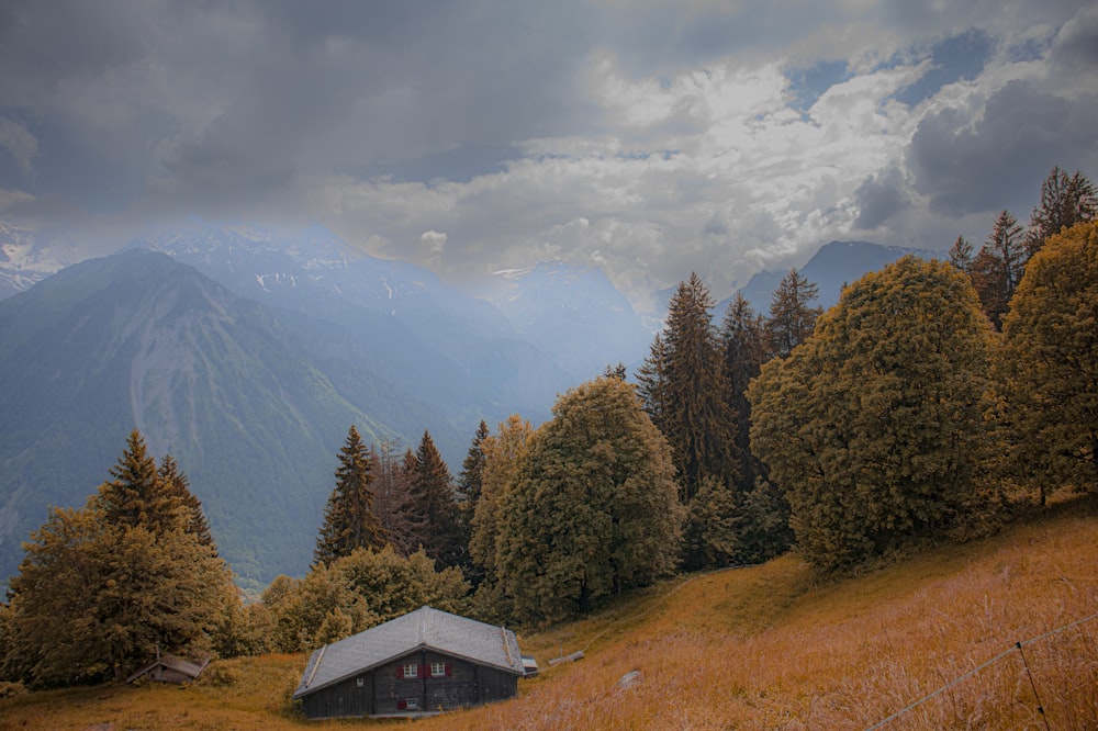 a house in the middle of a field with mountains in the background