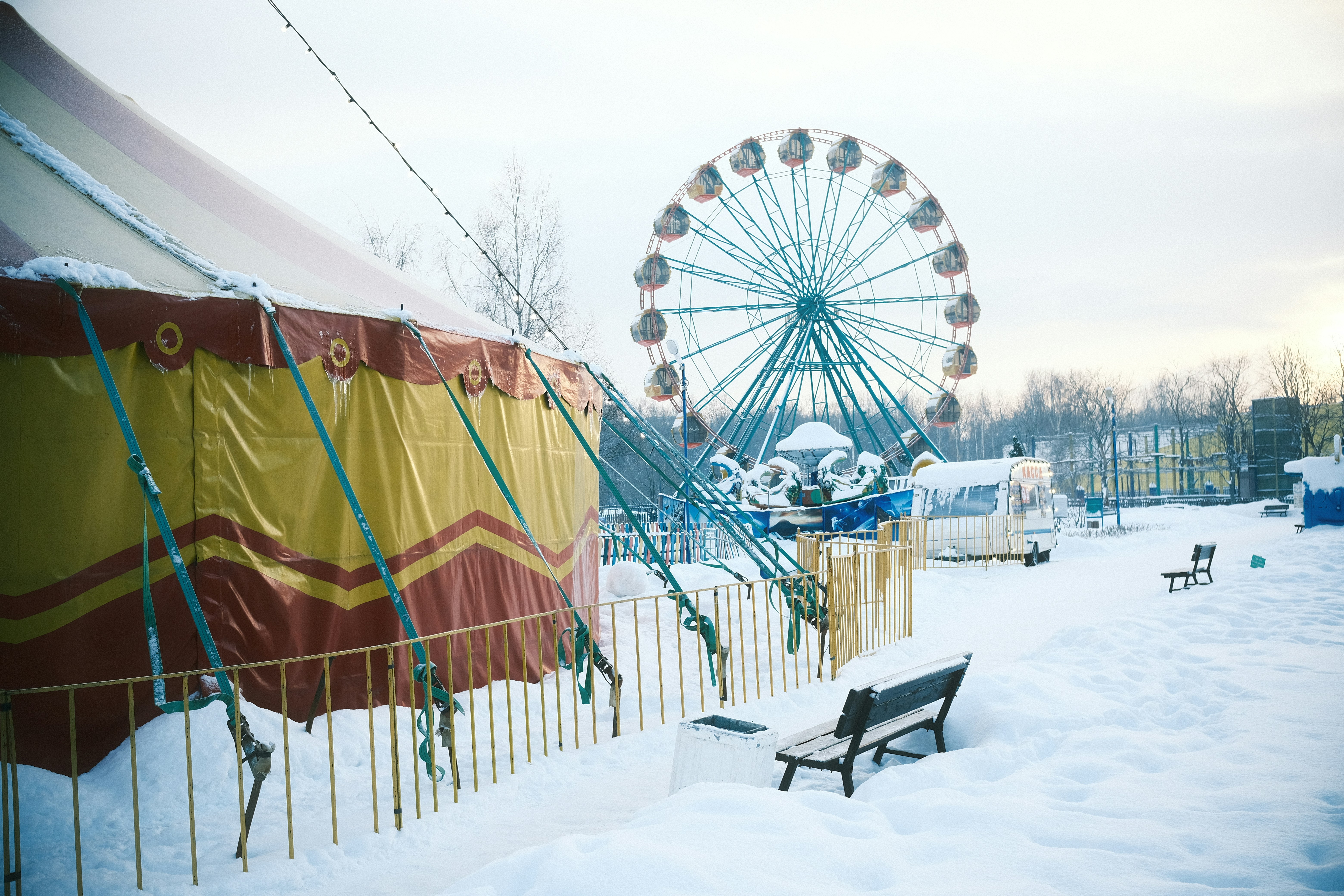 Un banco de parque cubierto de nieve junto a una noria