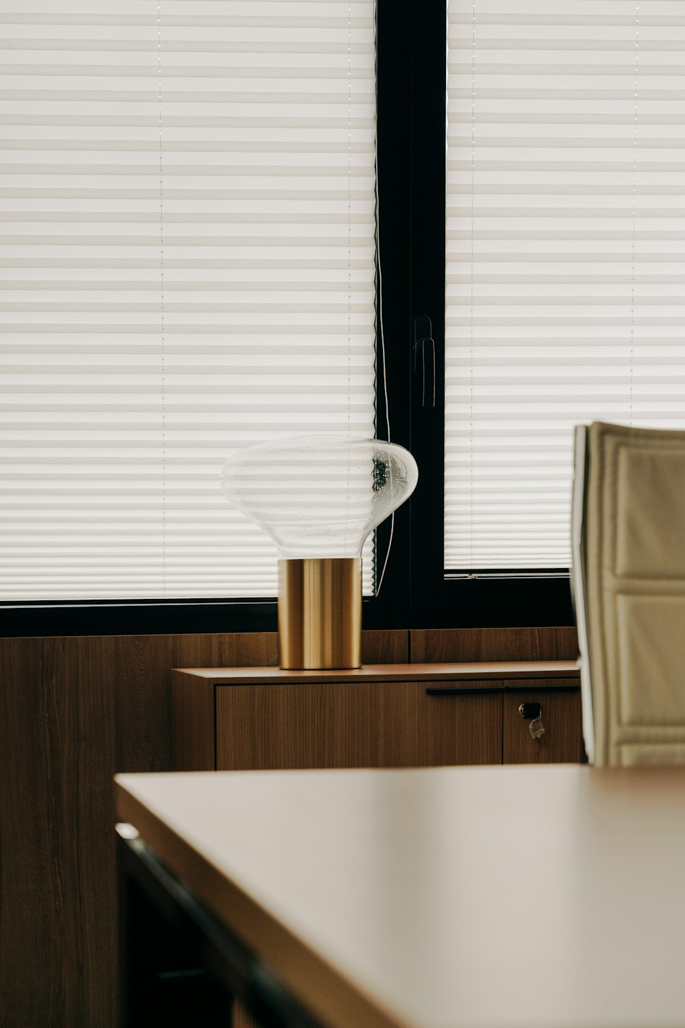 a room with a table, chair, and window with blinds