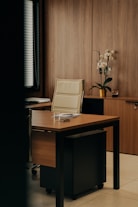 a desk with a chair and a vase of flowers