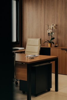 a desk with a chair and a vase of flowers