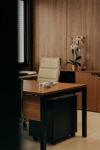 a desk with a chair and a vase of flowers