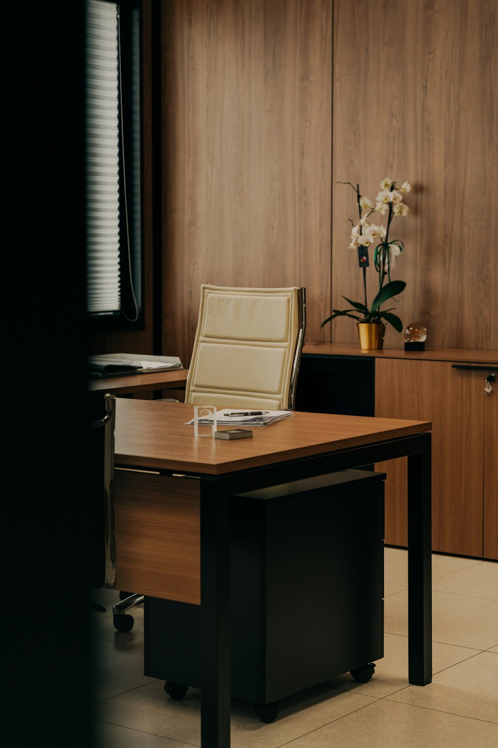 a desk with a chair and a vase of flowers