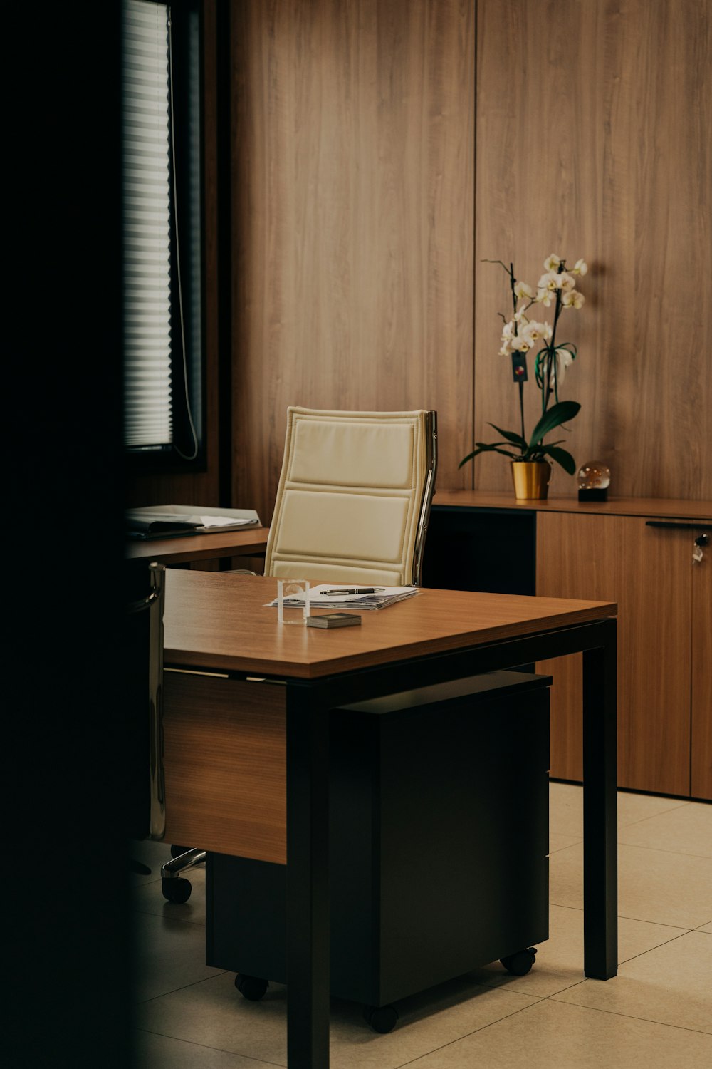 un bureau avec une chaise et un vase de fleurs