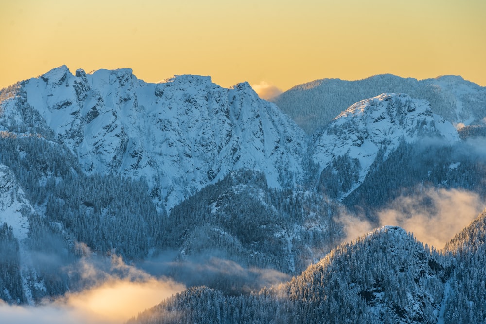 a mountain range covered in snow and clouds