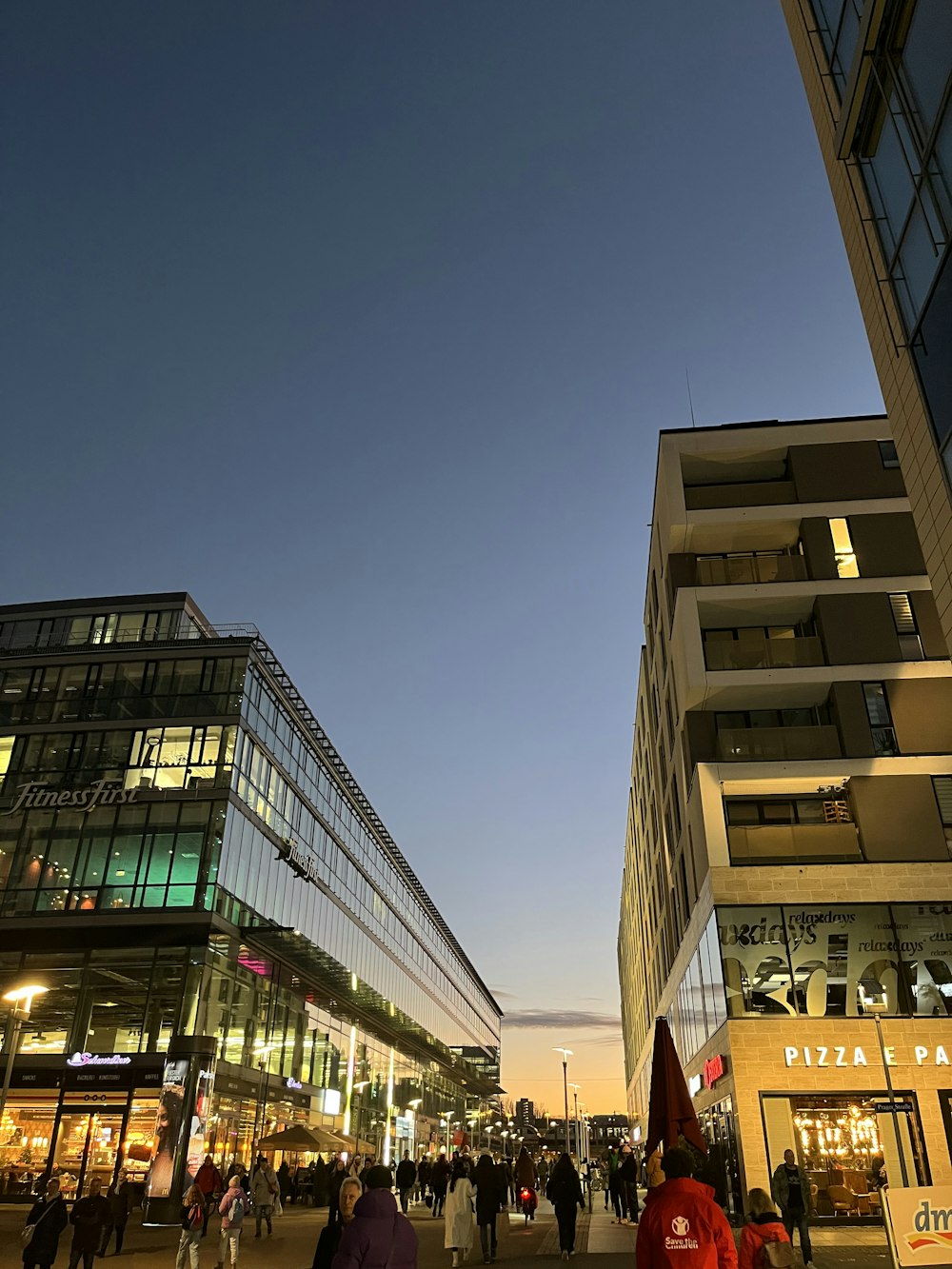 a group of people walking down a street next to tall buildings