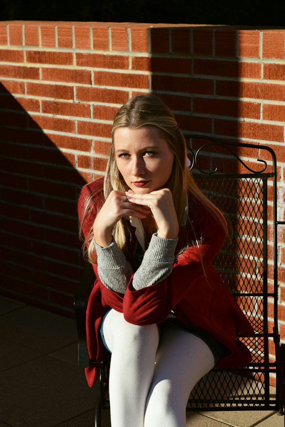 a woman sitting on a bench in front of a brick wall