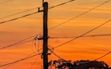 a telephone pole and wires against a sunset sky